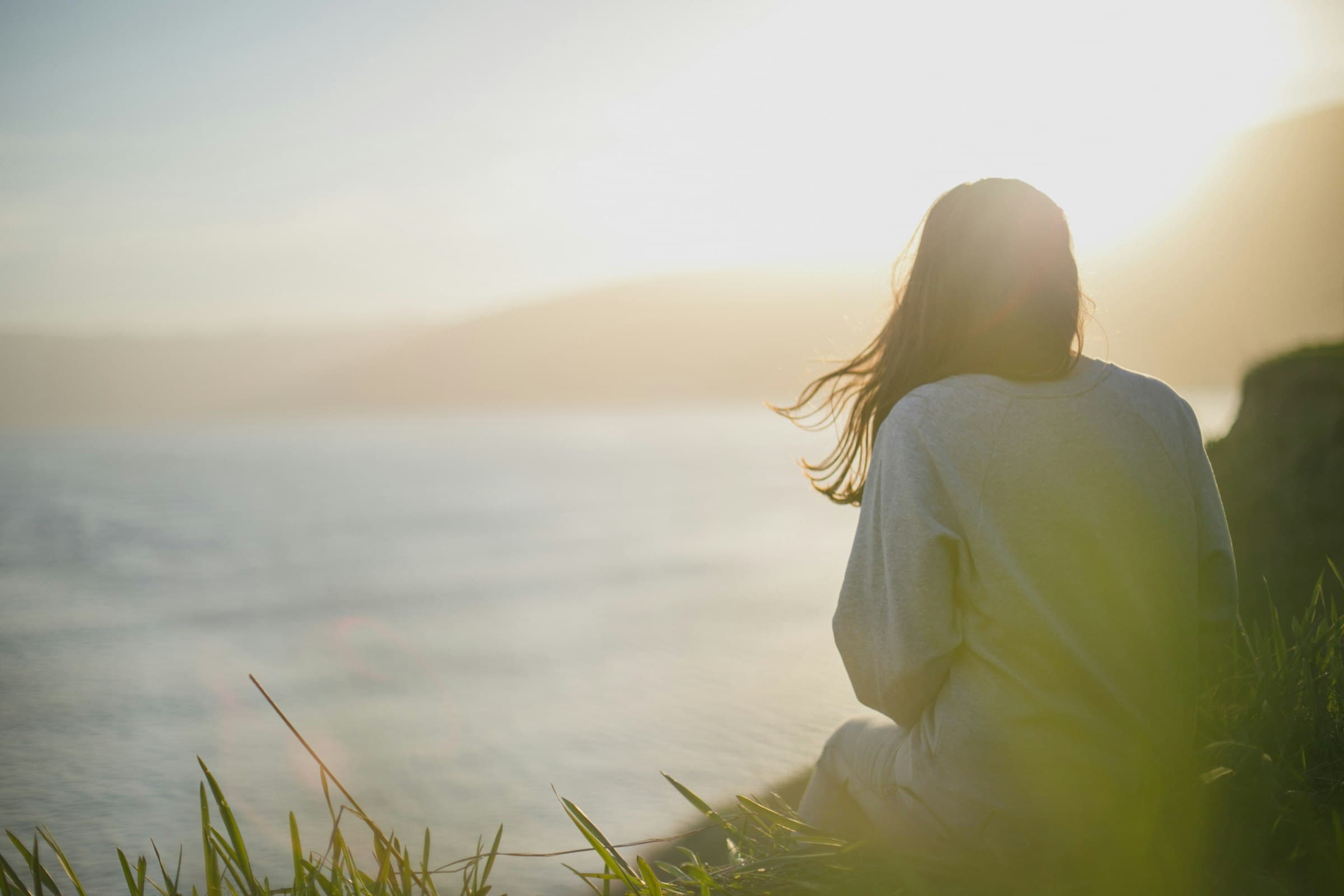 Persona meditando al atardecer en un paisaje natural, simbolizando paz y desconexión digital