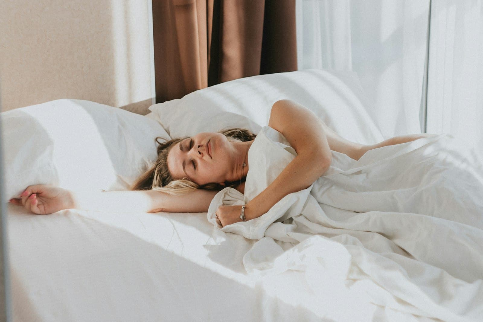 Una persona durmiendo tranquilamente en una cama con sábanas blancas, envuelta en paz.