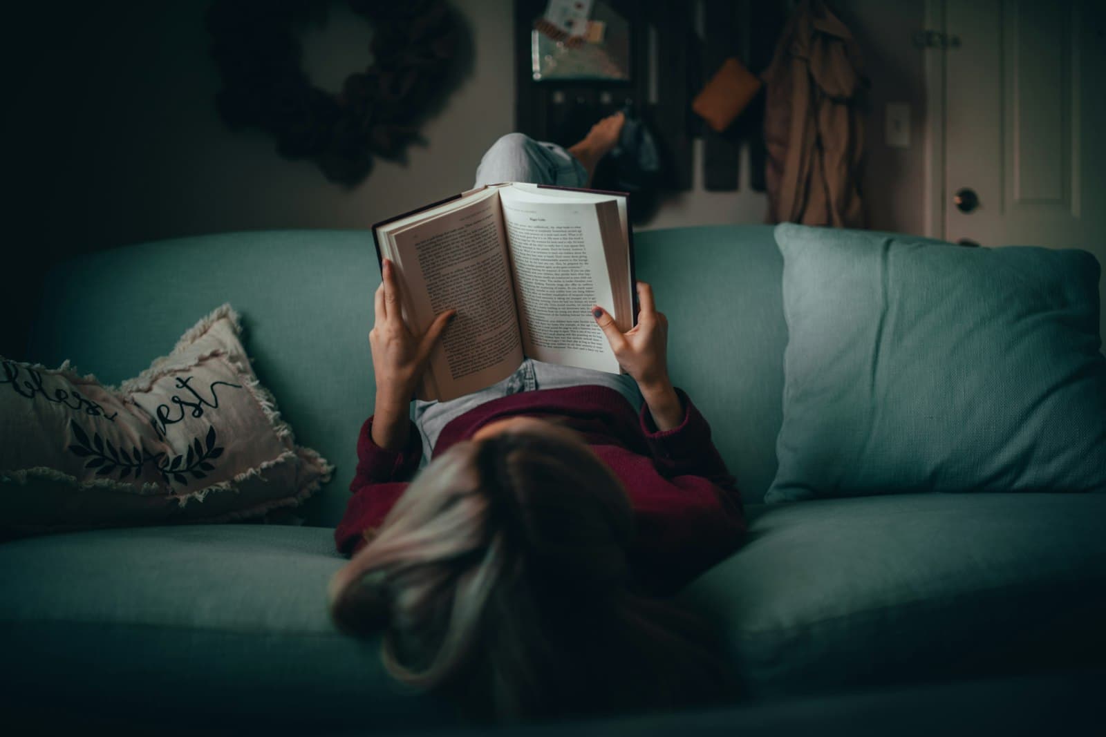 Una persona leyendo un libro con una luz cálida, preparándose para el sueño.