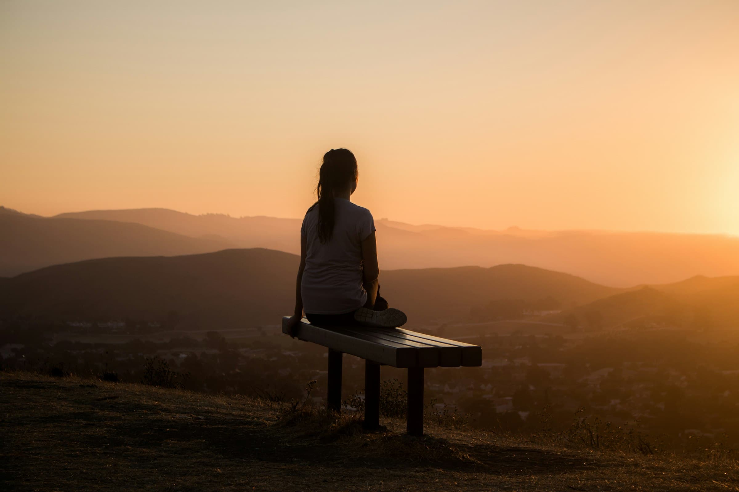 Una persona en postura de meditación con ojos cerrados, respirando profundamente en un entorno sereno.