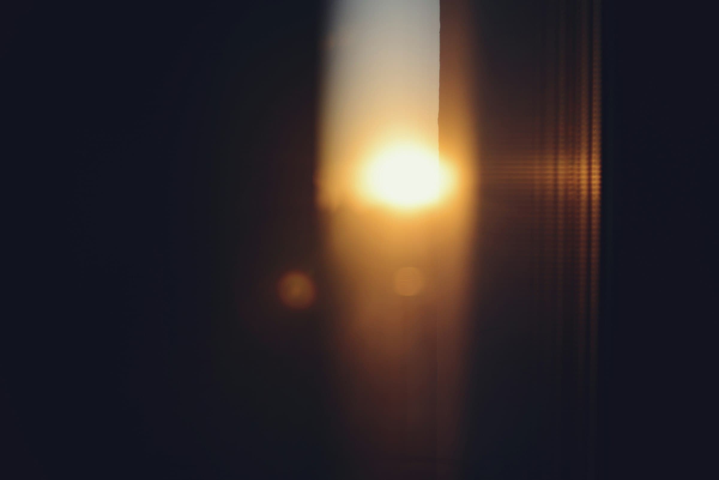 Una mujer en silueta meditando frente a una ventana al amanecer, con luz suave y cálida.