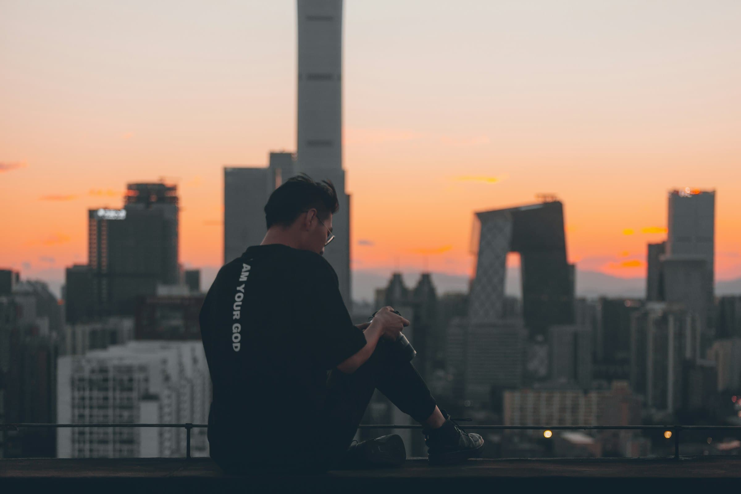 Una persona meditando tranquilamente en una azotea de la ciudad al amanecer, con el horizonte urbano de fondo