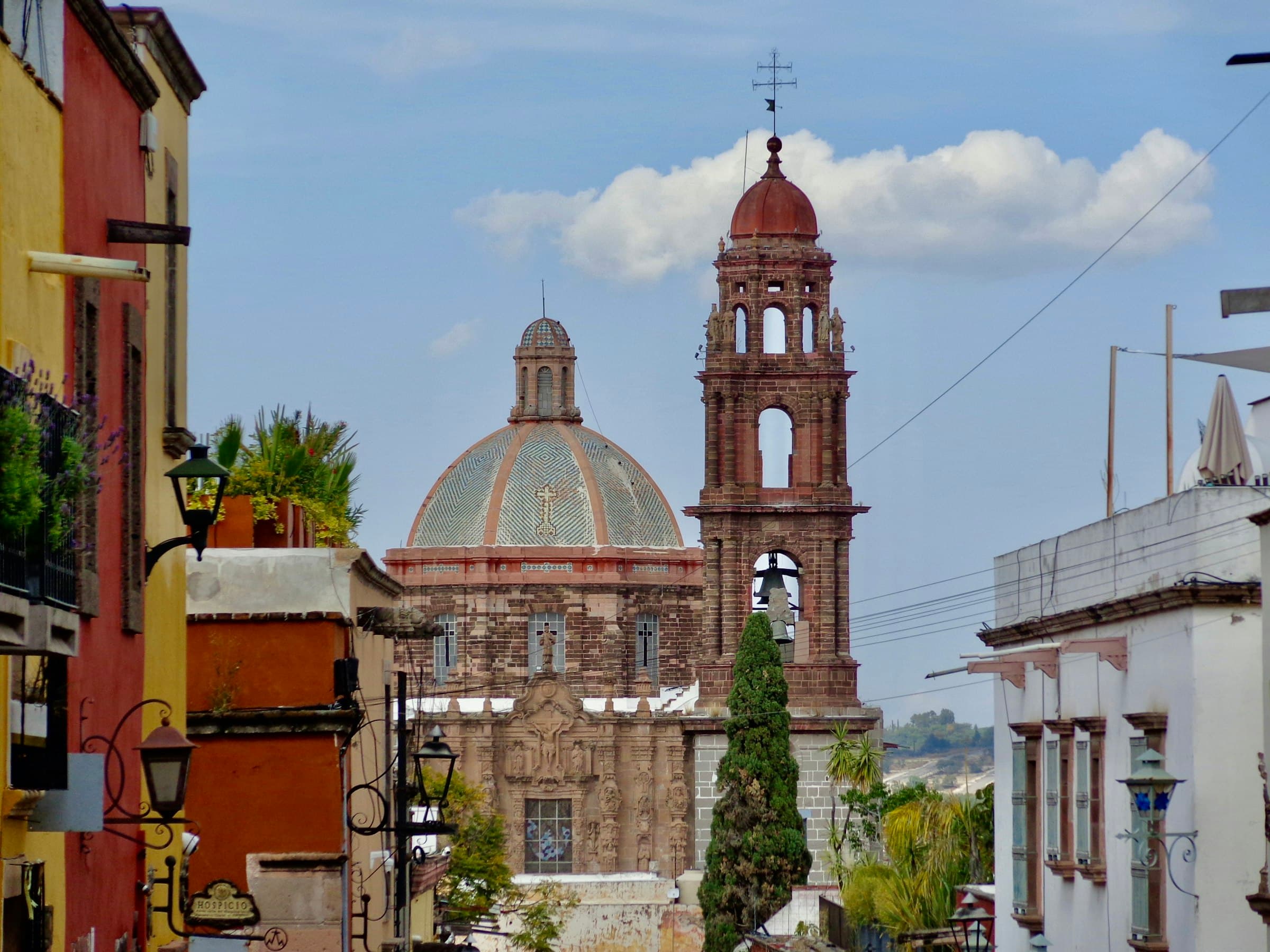 Vista de los tejados coloniales de San Miguel de Allende al atardecer, con la Parroquia de San Miguel Arcángel al fondo.