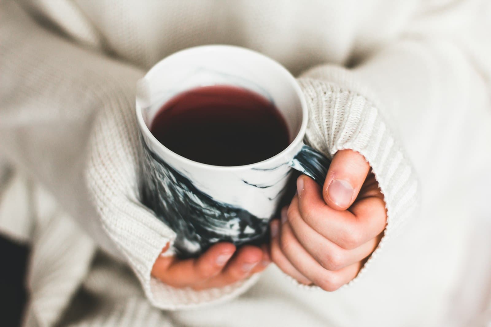 Manos sosteniendo una taza de té caliente en un ambiente acogedor nocturno
