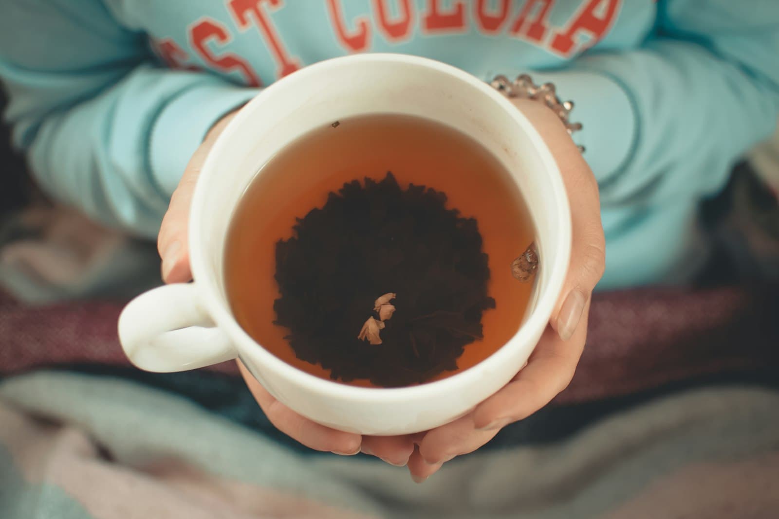 Manos sosteniendo una taza de té humeante con suavidad en una mañana tranquila.