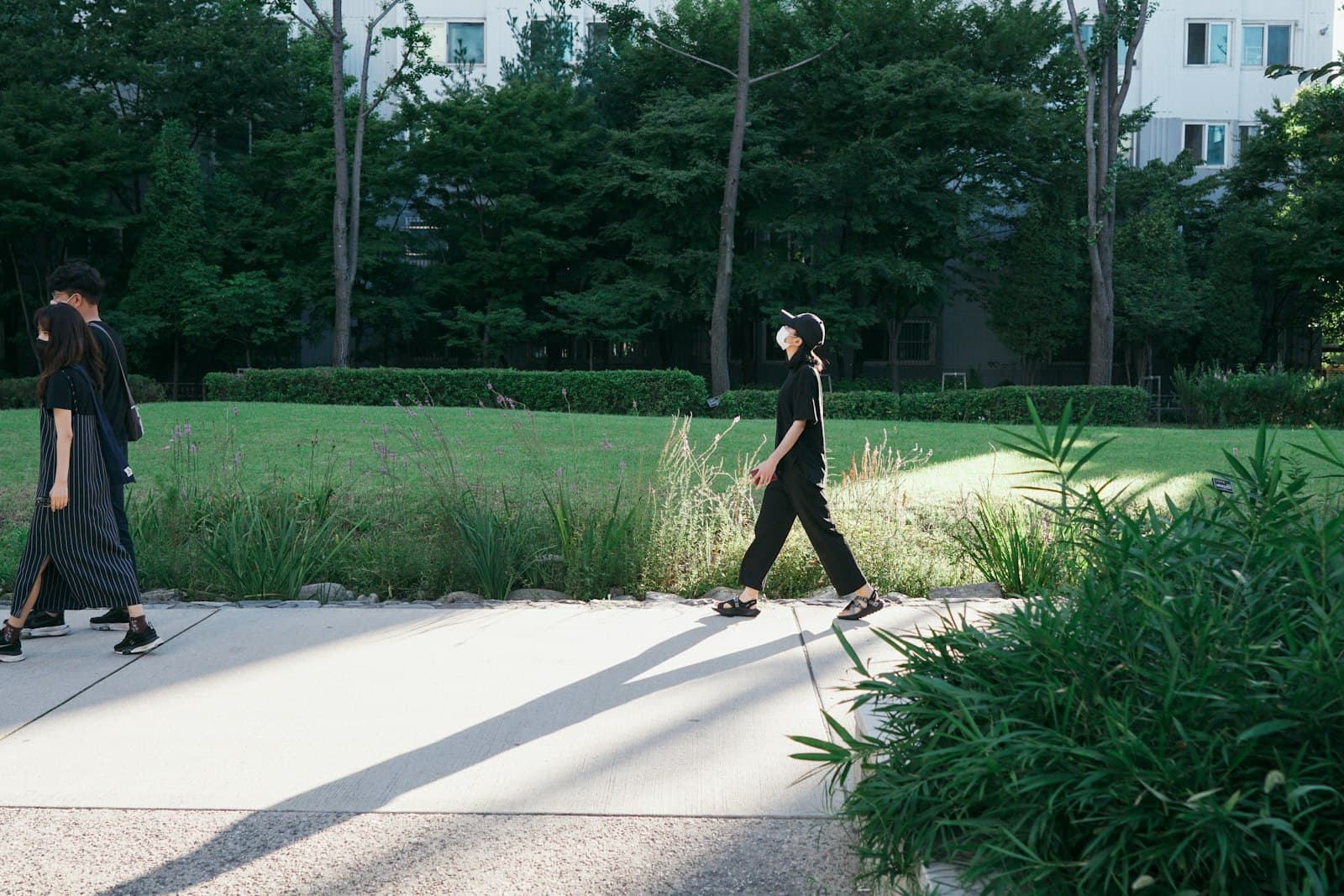 Persona caminando serenamente en un parque urbano, con árboles y edificios al fondo