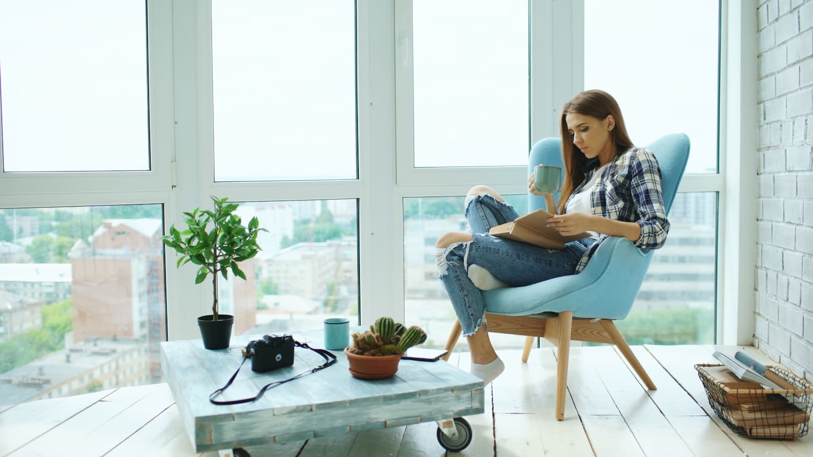 Una mujer bebiendo té lentamente, contemplando la vista desde la ventana de su apartamento en la ciudad