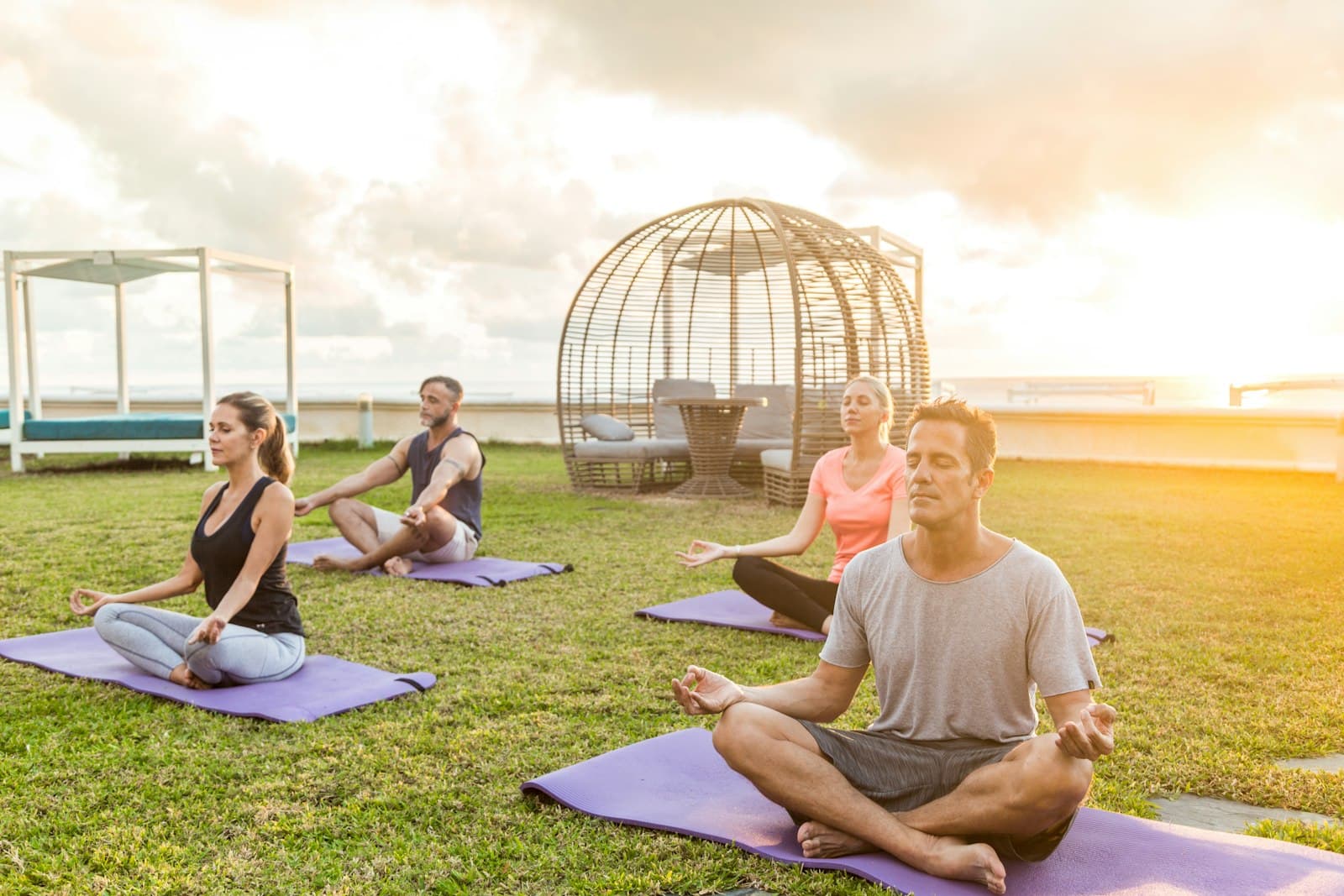 Varias personas practicando yoga en un espacio abierto, mostrando diferentes niveles y cuerpos.